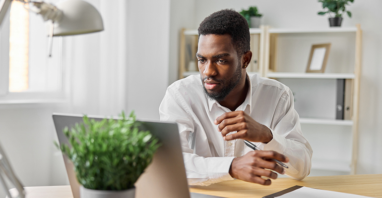 Person attending online therapy session on laptop at home, looking calm and focused